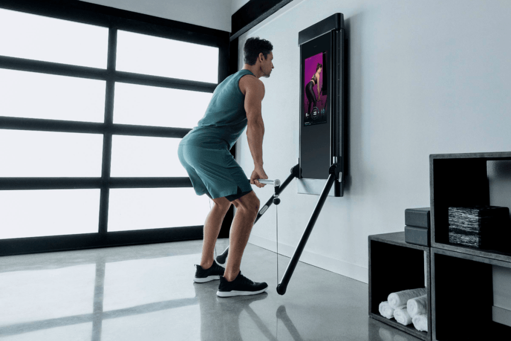A man is working out in his garage, using Tonal to complete an RDL.