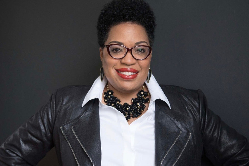 a woman wearing a black leather jacket and shirt and smiling at the camera