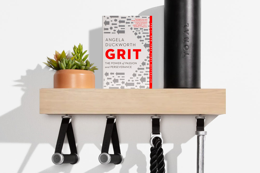 An image of the book "Grit" by Angela Duckworth sitting on a Tonal shelf illustrating that "Grit" is the April