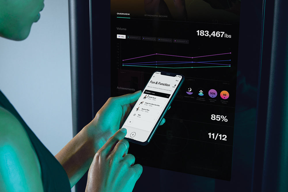 Woman reviewing a custom strength training program on Tonal.