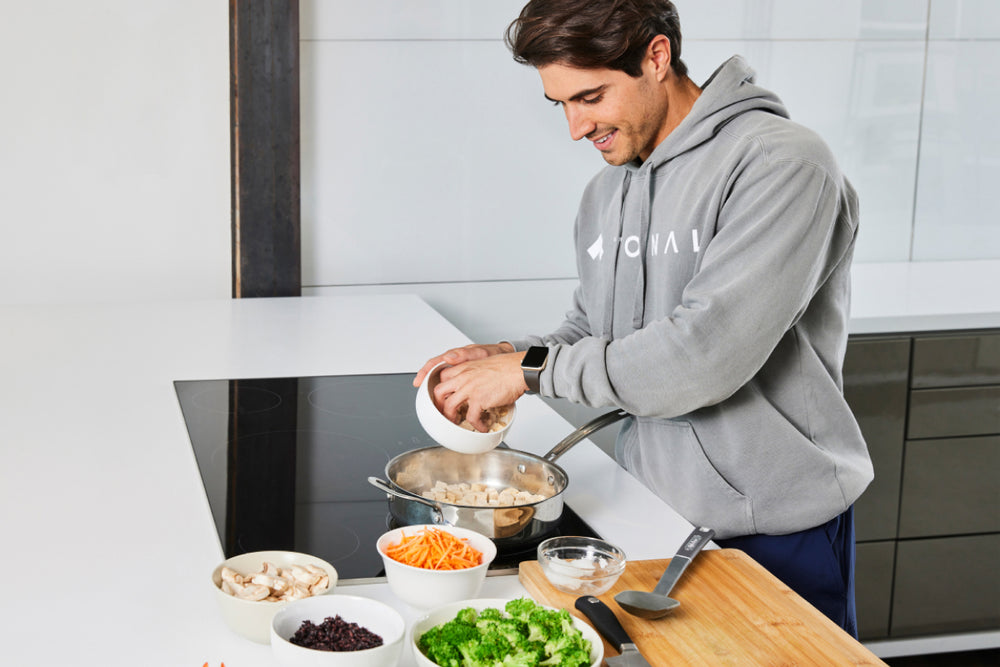 a man putting tofu into a skillet in the kitchen