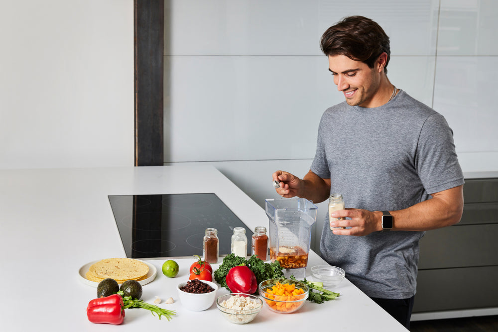 Image of a man adding ingredients to a blender for sauce to top a vegetarian taco recipe