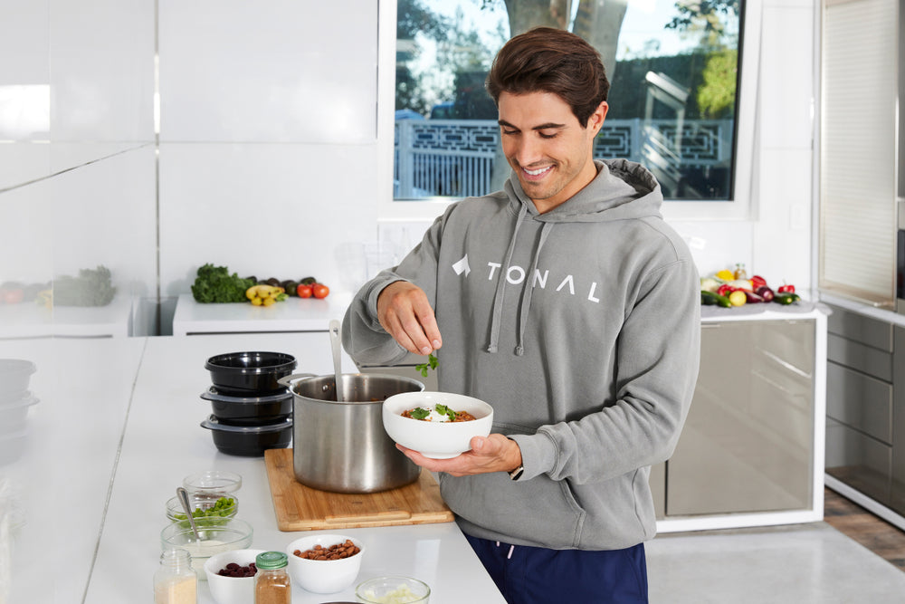 image of a man sprinkling a bowl of  with cilantro demonstrating his vegetarian chili recipe