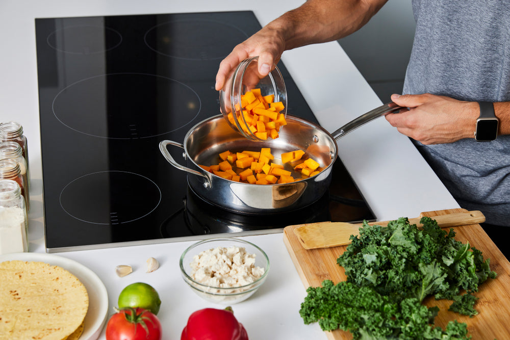 Person preparing meal at a stove top with vegetables; healthy eating habits