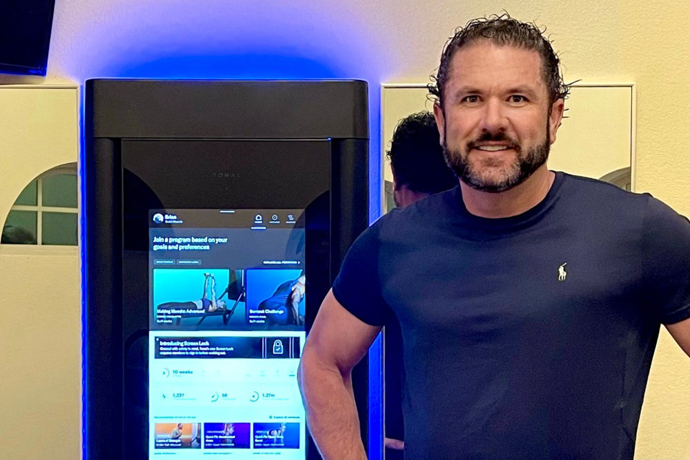 a man standing with his tonal exercise machine and smiling