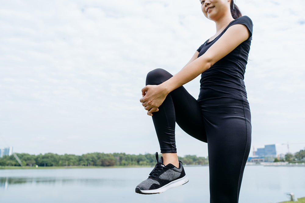 Woman pulling her knee in doing knee-strengthening exercises.