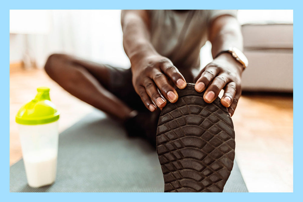 Man stretching next to a shaker bottle  with pre-workout supplements.