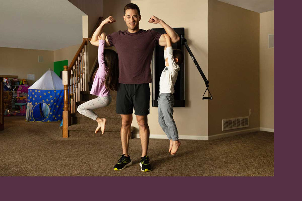 John Sill lifting up two of his kids on his biceps