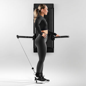 Tonal coach Kendall 'Woody' Wood performing a standing leg extension on Tonal using ankle straps.