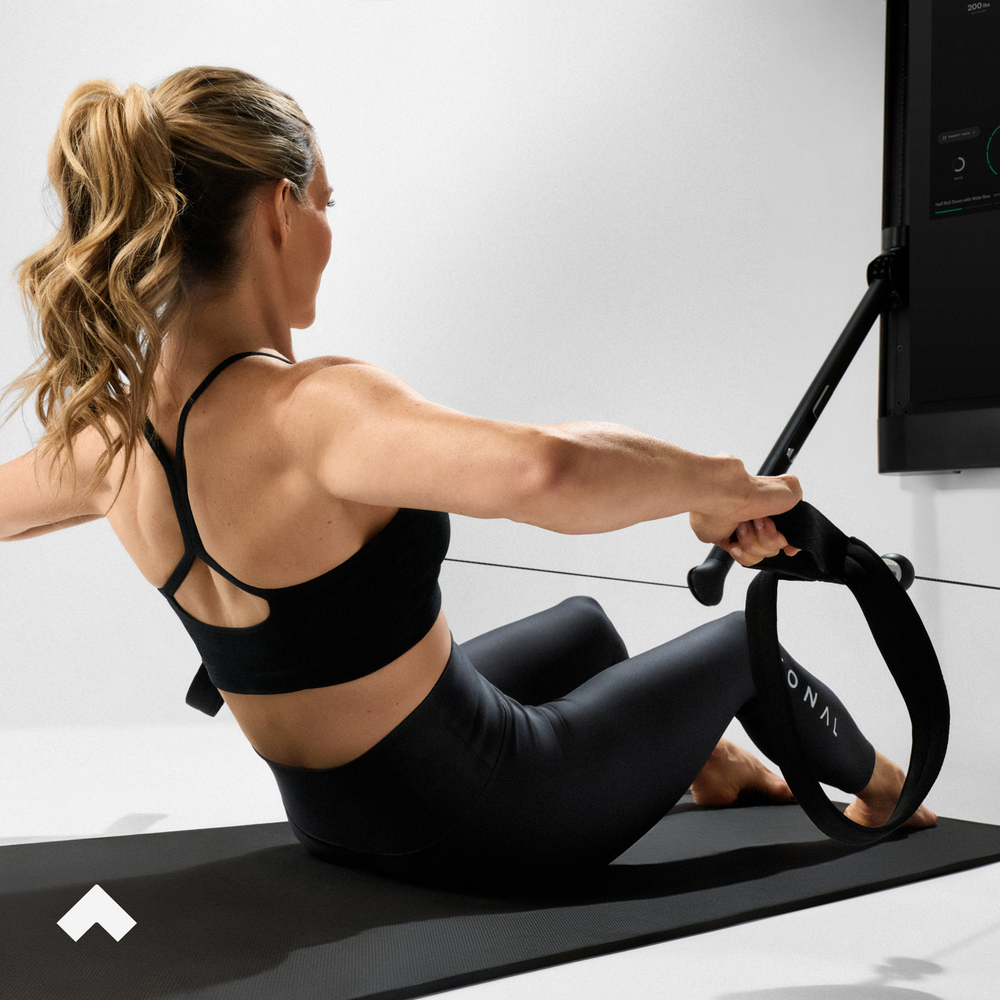 Woman doing Pilates on a Tonal machine in a studio setting.