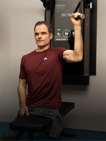 Man exercising on a tonal machine mounted to the wall
