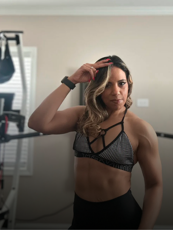 Person wearing a black sports bra and leggings in a home setting.