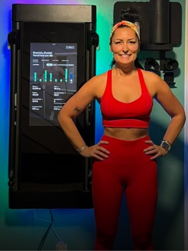 Woman in red athletic wear standing next to a piece of exercise equipment with a colorful background.