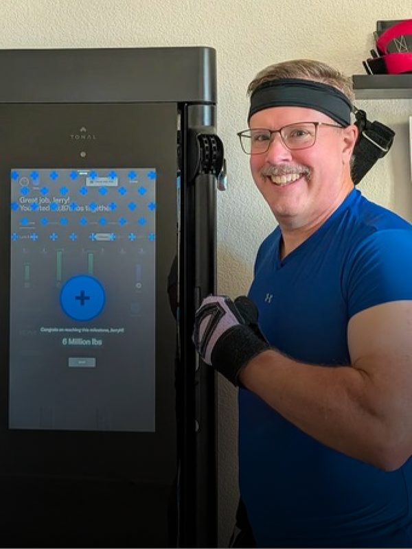 Person wearing a blue shirt and black headband standing next to a machine with a digital display.