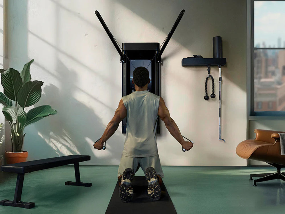 Man exercising with a machine, Tonal, in a home gym setting.
