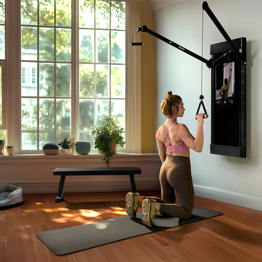 Woman performing single arm lat pulldown using the Tonal training system mounted on a wall in her home