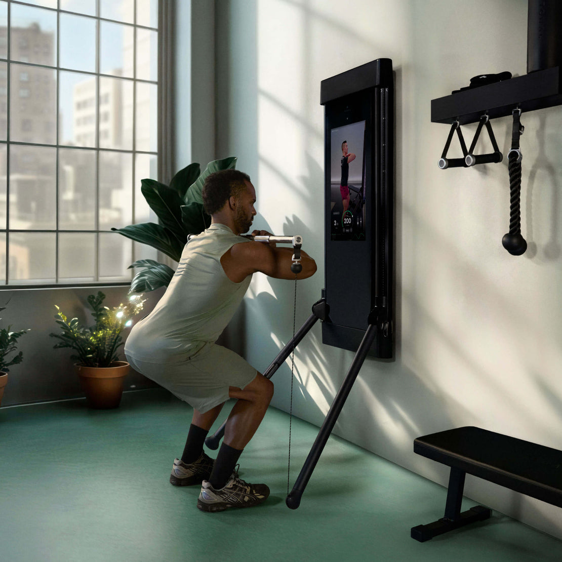 Person performing a squat with the Tonal Bar and Bar Control Module with a Tonal fitness device displaying an app interface.