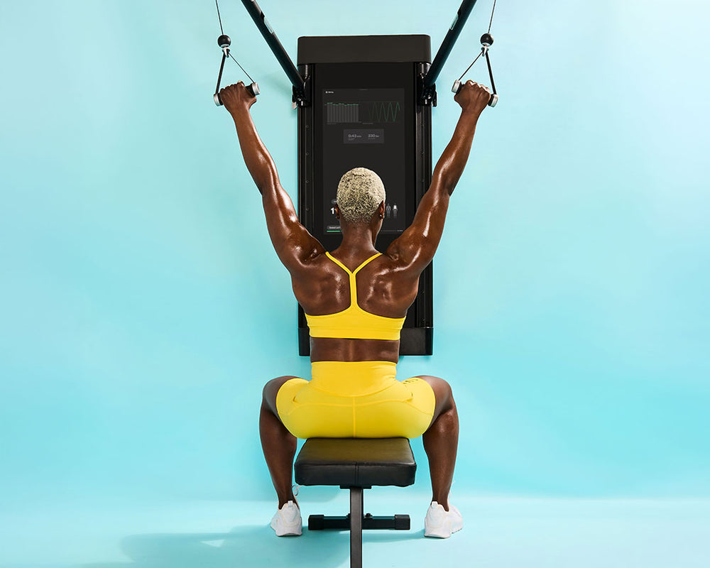 Tonal coach Tanysha performs a lat pulldown to exercise her back.