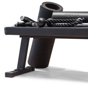 Black tonal workout bench, black workout mat, black workout roller, and black rope attachments