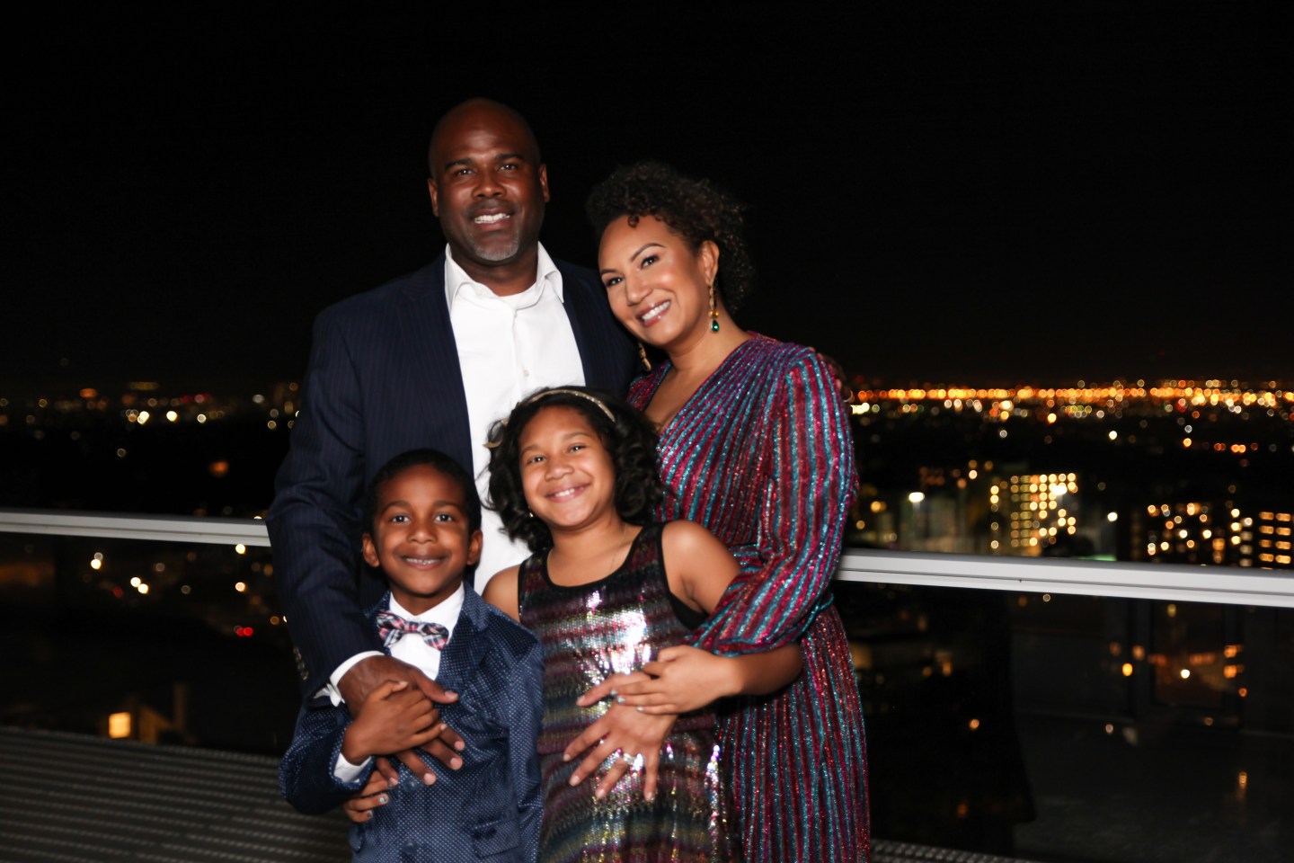 a man standing on a balcony with his family smiling