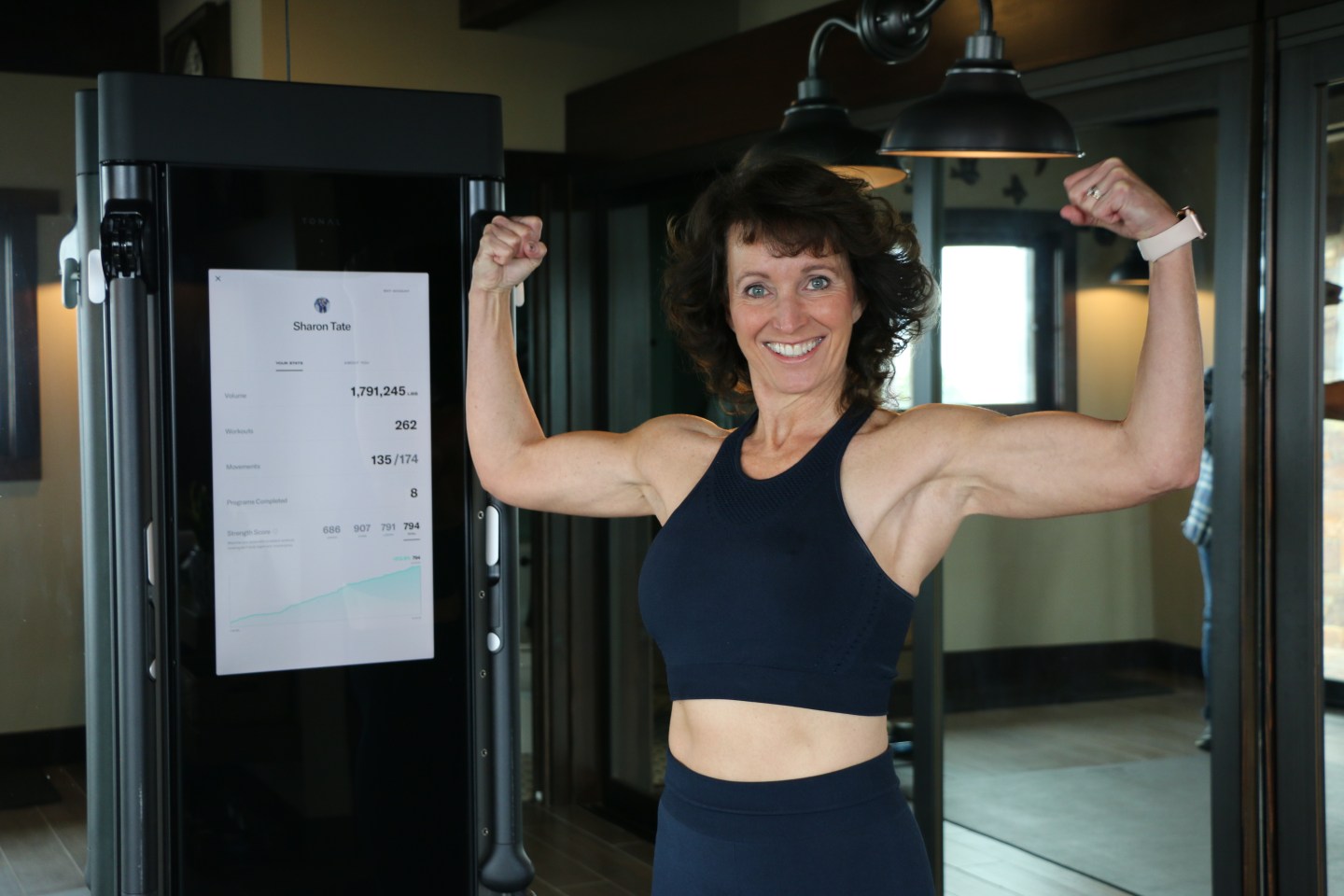 a woman smiling holds up her biceps proudly 