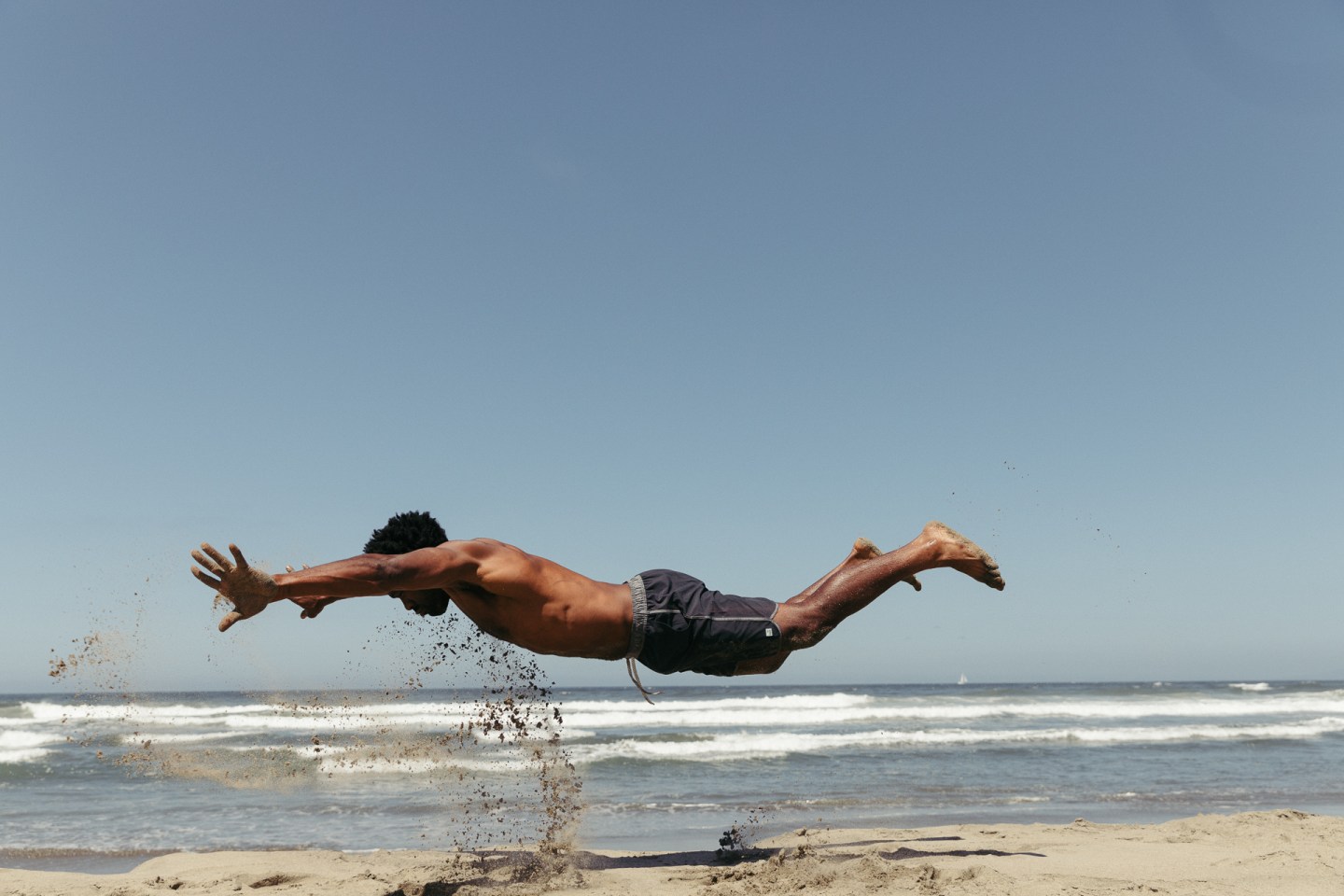 a man doing a body jump on the beach