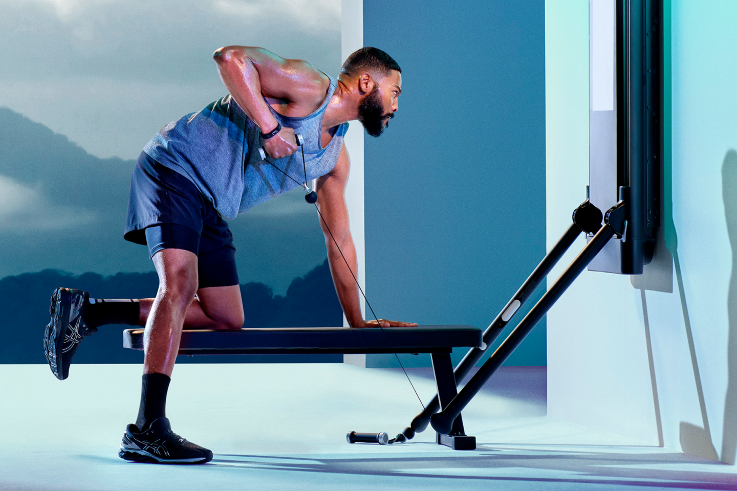 a man working on tonal doing an arm row with one knee on a bench